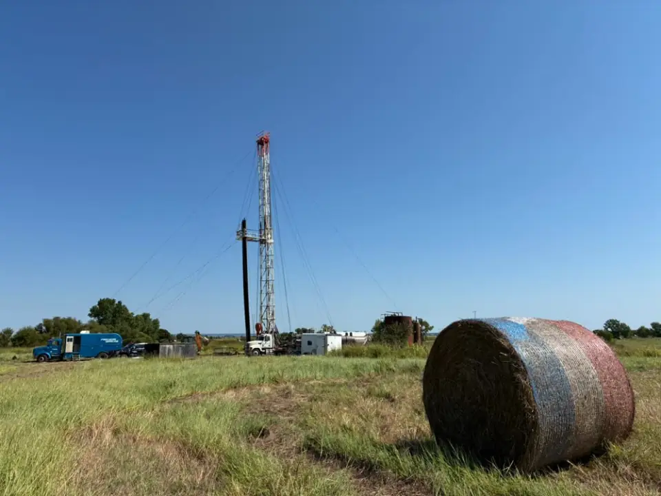 A plugging rig on a well site in open pasture, with a hay bale in the foreground