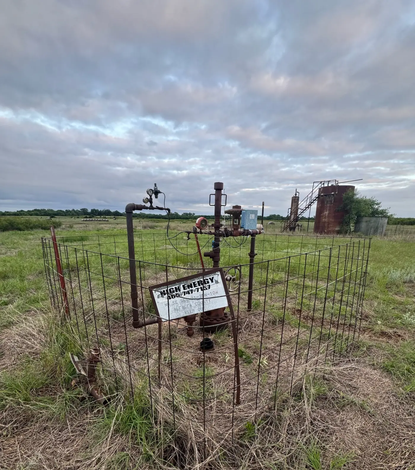 The Schnitzer #2 wellhead inside a wire fence on the Oklahoma prairie, as found in May 2025